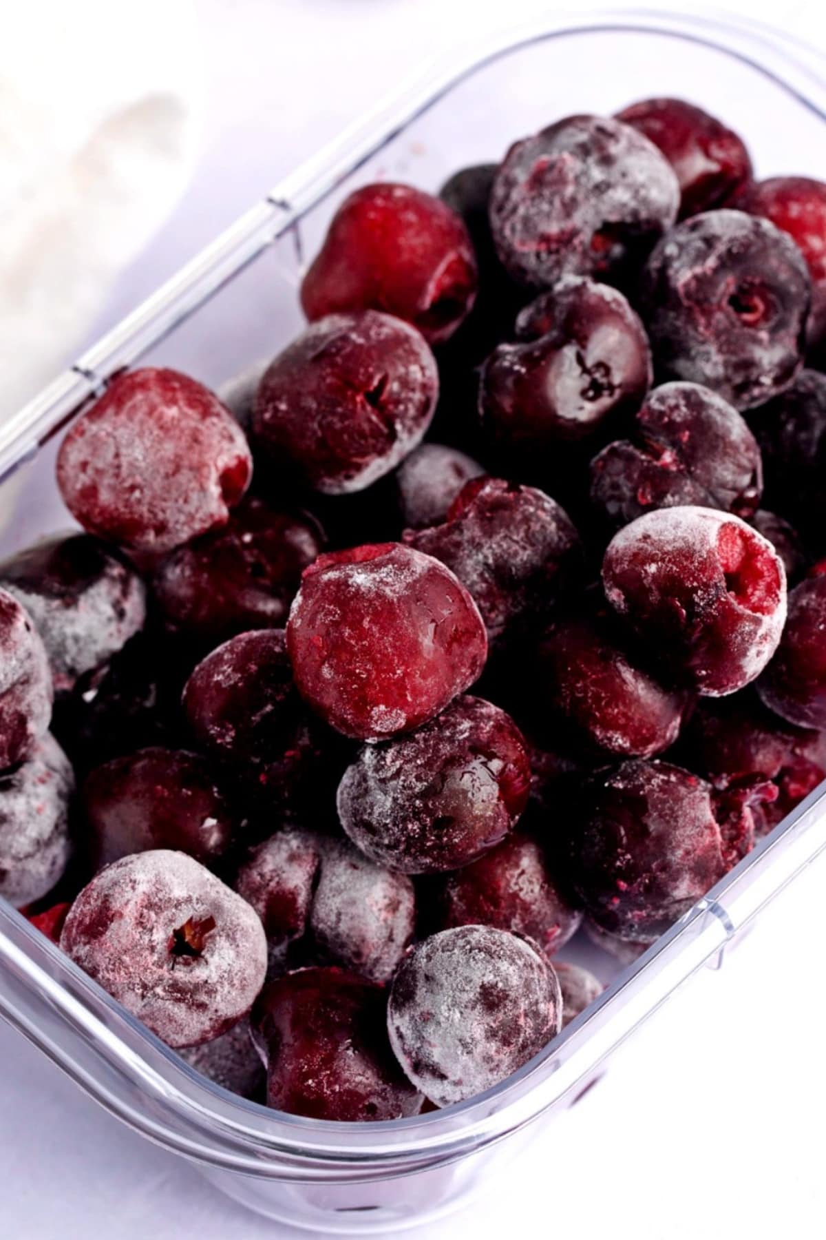 Frozen cherries on a clear bowl in a white marble table. 