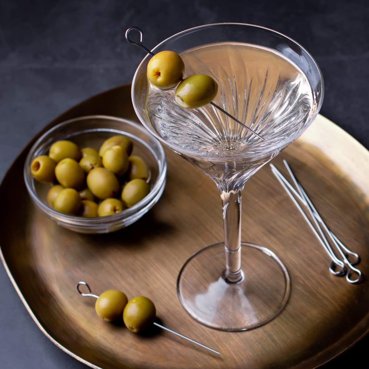 Glass of Dirty Martini Garnished With Olives on Stick