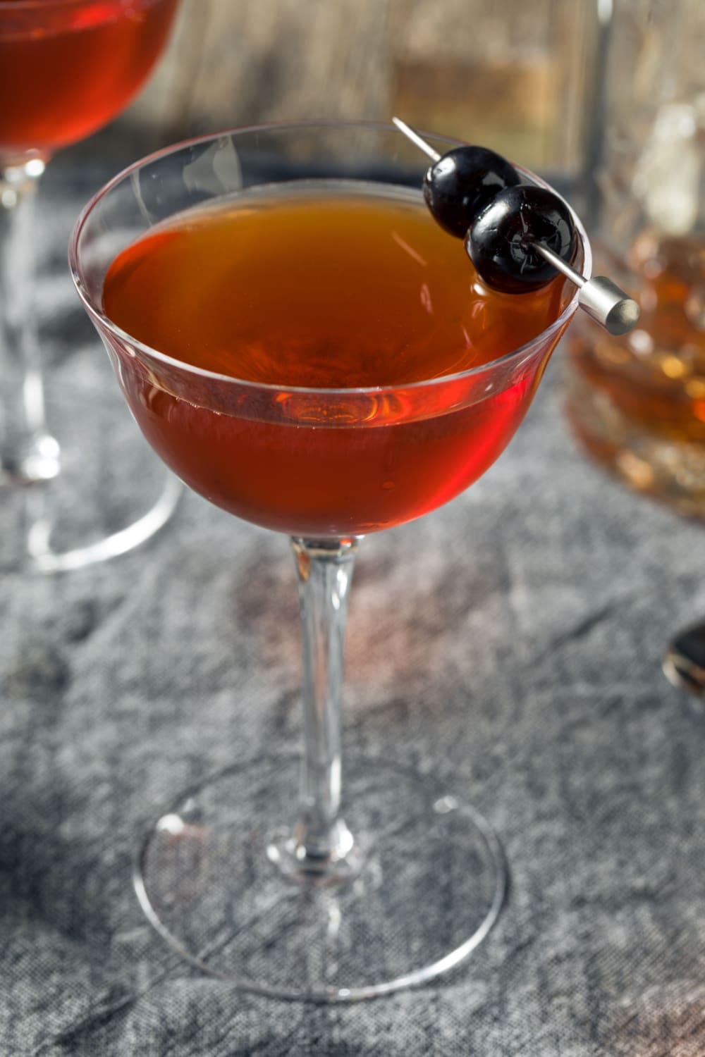 Rob Roy Cocktail served in a tall cocktail glass with black cherries served as garnished
