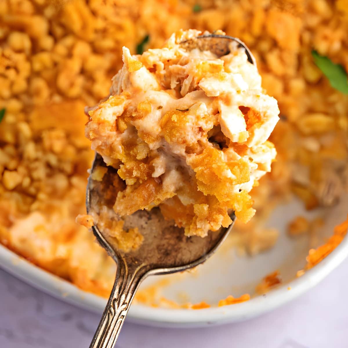 A Spoonful of Creamy Million Dollar Chicken Casserole with Crunch Ritz Topping, Full Casserole in Background