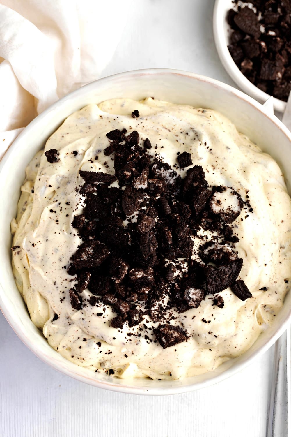 Big Bowl of Oreo Fluff, Topped with Crushed Oreos and a Bowl of Crushed Oreos Behind to the Right