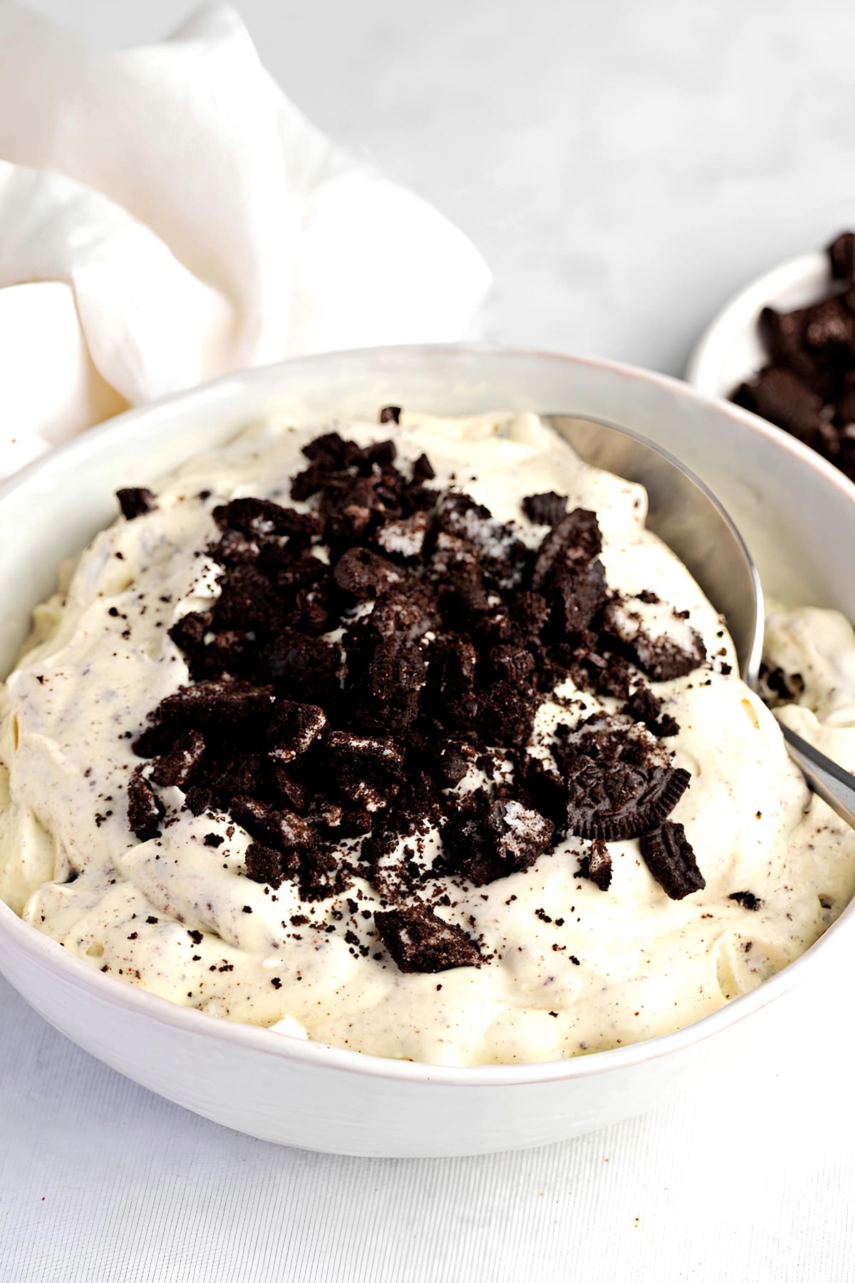 Easy Oreo Fluff featuring Oreo Fluff in a White Bowl Topped with More Oreo Crumbles