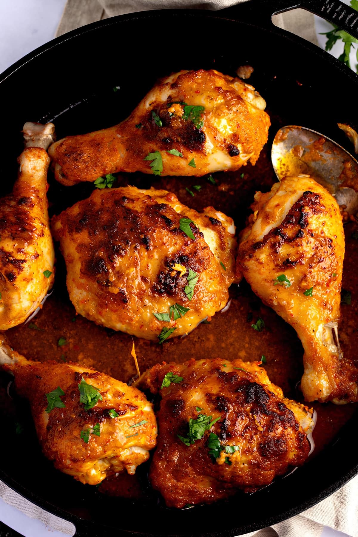 Chicken Peri-peri cooked in a skillet with sauce and herbs.