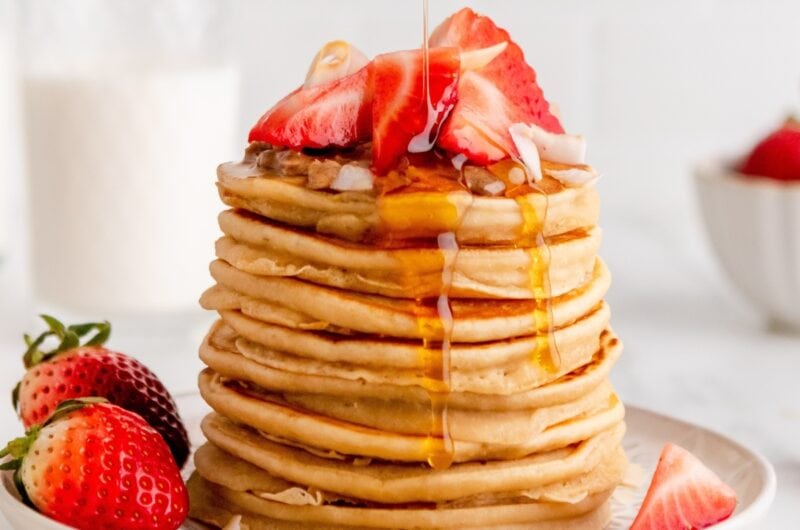 Pouring Maple Syrup on a Pancake with Fresh Strawberries on Top