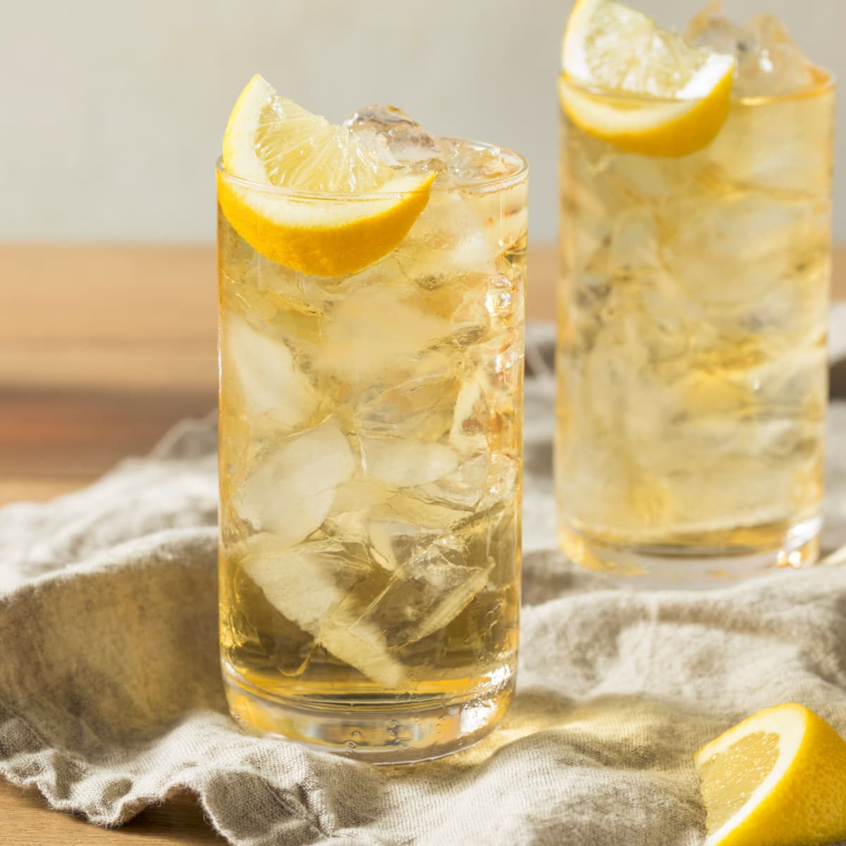 Two glasses of Lynchburg Lemonade served in a highball glass, filled with ice garnished with lemon slice.