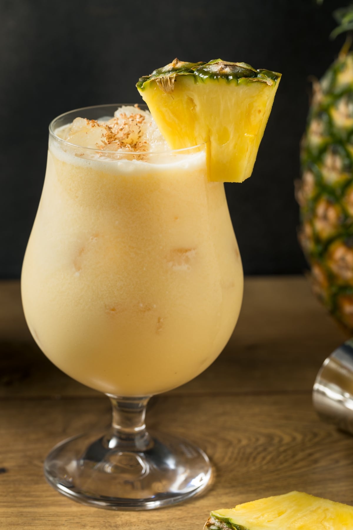 Classic Painkiller Cocktail (Best Recipe) featuring A glass of Painkiller Cocktail with a Pineapple Wedge