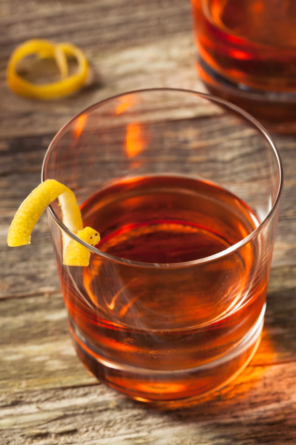 Sazerac Cocktail on an old fashioned glass on a wooden table garnished with lemon peel