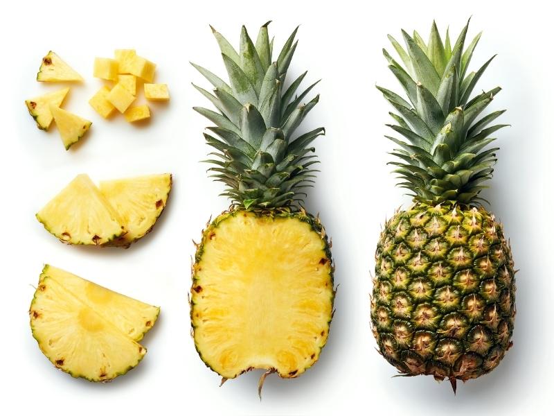 Several pieaces of pineapple arranged on a white surface