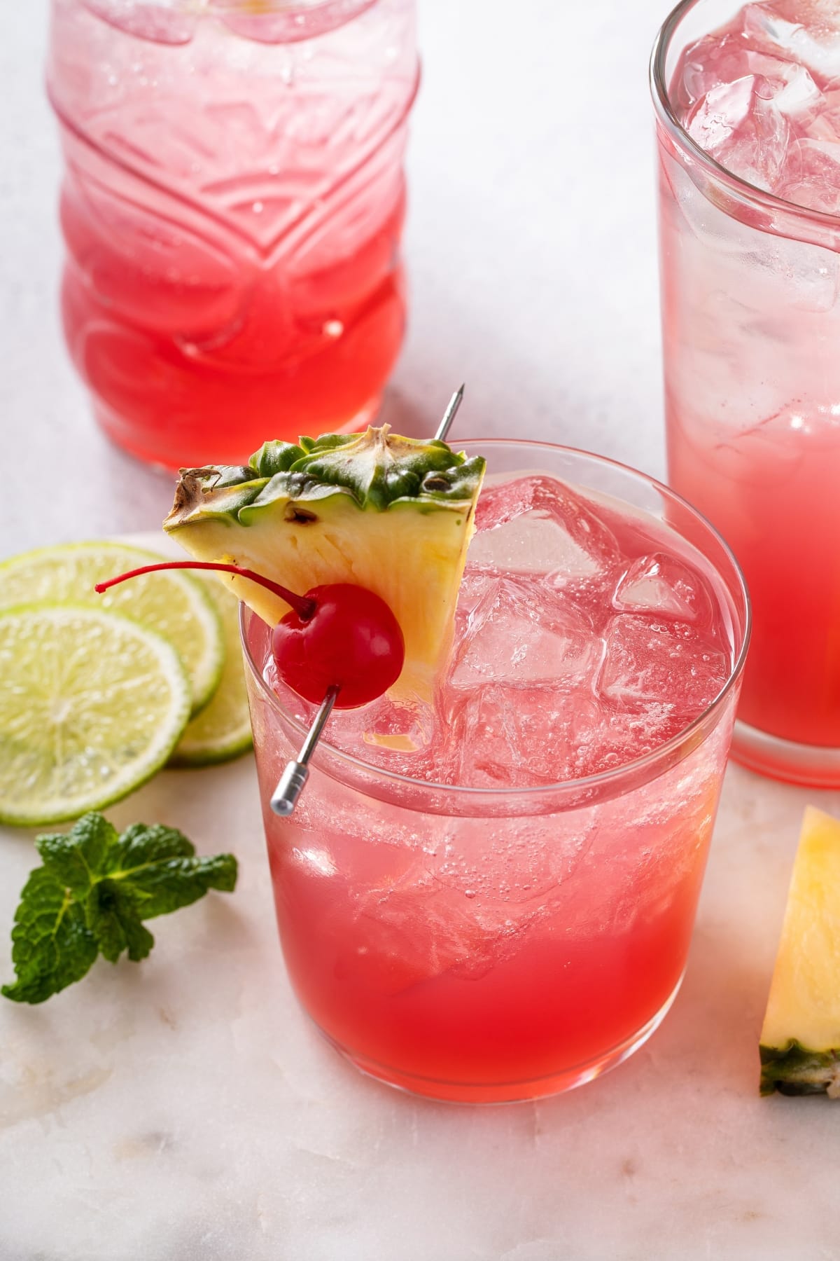 Singapore Sling Cocktail (Best Recipe) featuring 3 glasses of Refreshing Singapore Cocktail Garnished With Fresh Pineapple and Cherry