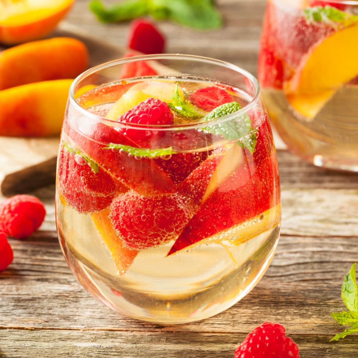 Boozy refreshing raspberries and peach white sangria on a wooden table