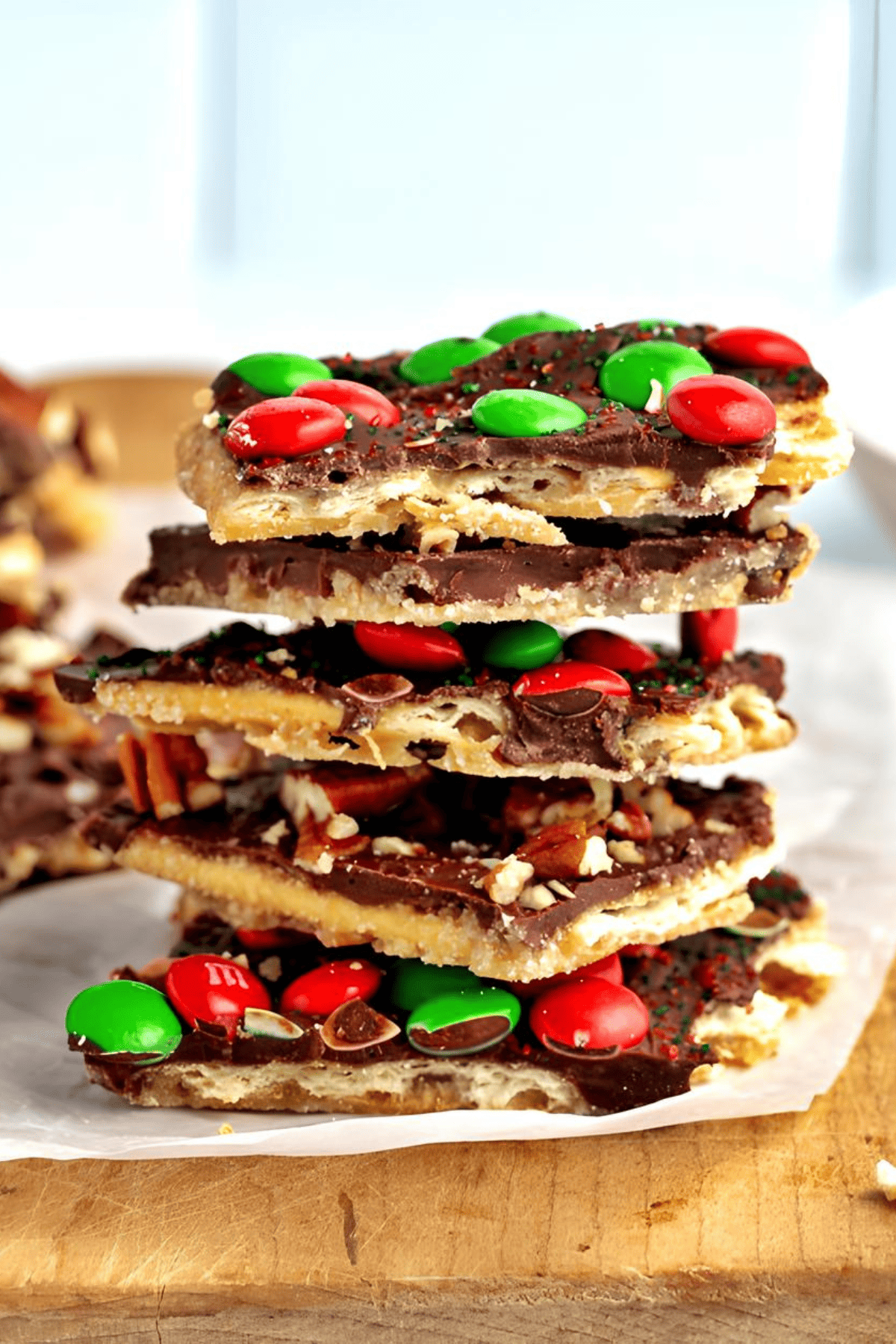 Christmas Crack (a.k.a. cracker toffee)  topped with colorful M&M's candies, stacked together on parchment paper