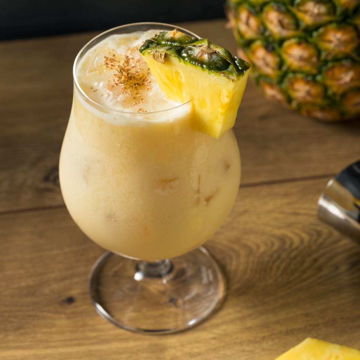 Top view of a glass of Painkiller Cocktail,  garnished with a slice of fresh pineapple and nutmeg powder