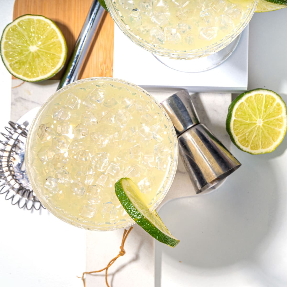 Top view of two coupe filled with a refreshing lime-infused gimlet cocktail, garnished with zesty lime wheel on the rim