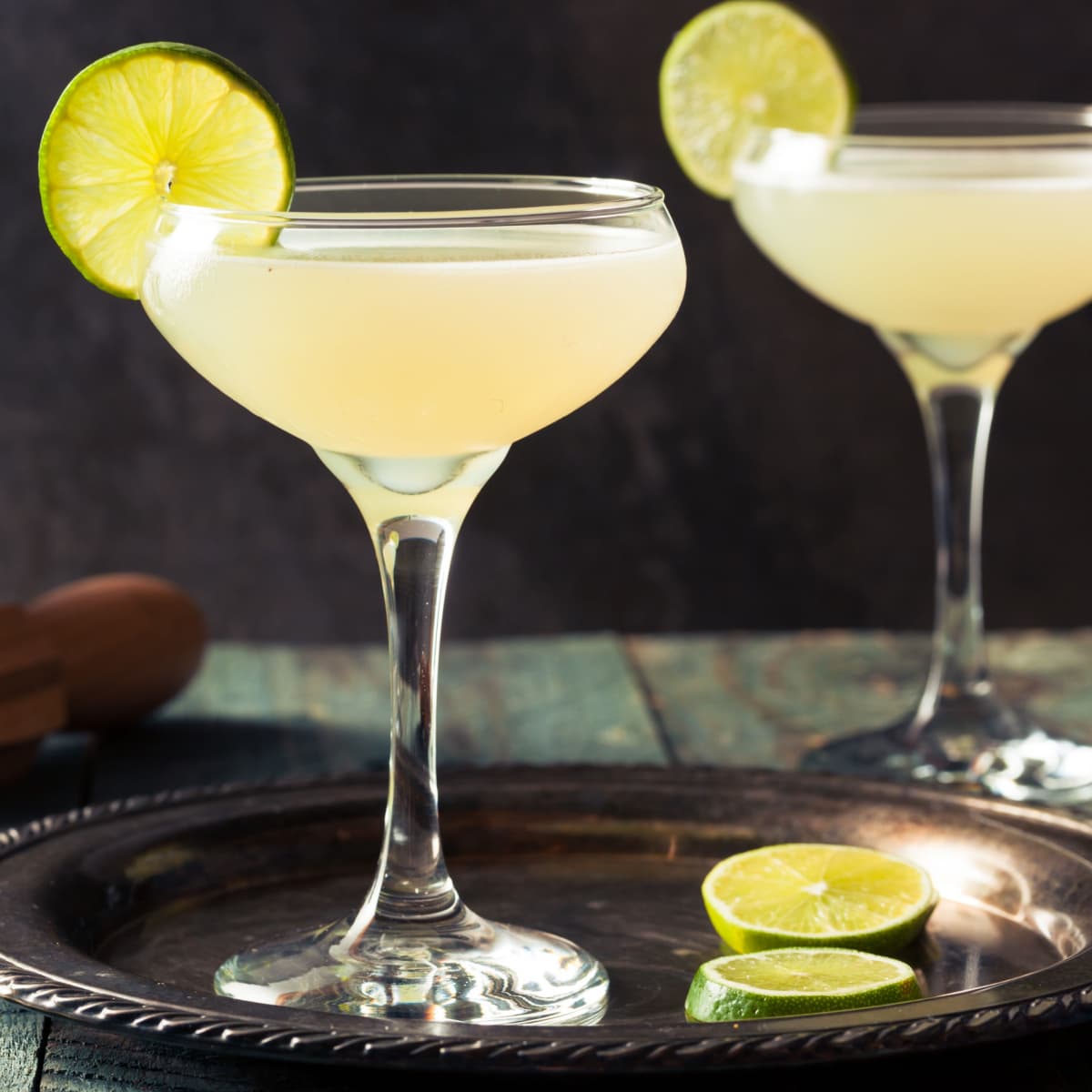 Two Glasses of Refreshing Daiquiri Cocktails, One on a Serving Tray with Lime Wheels