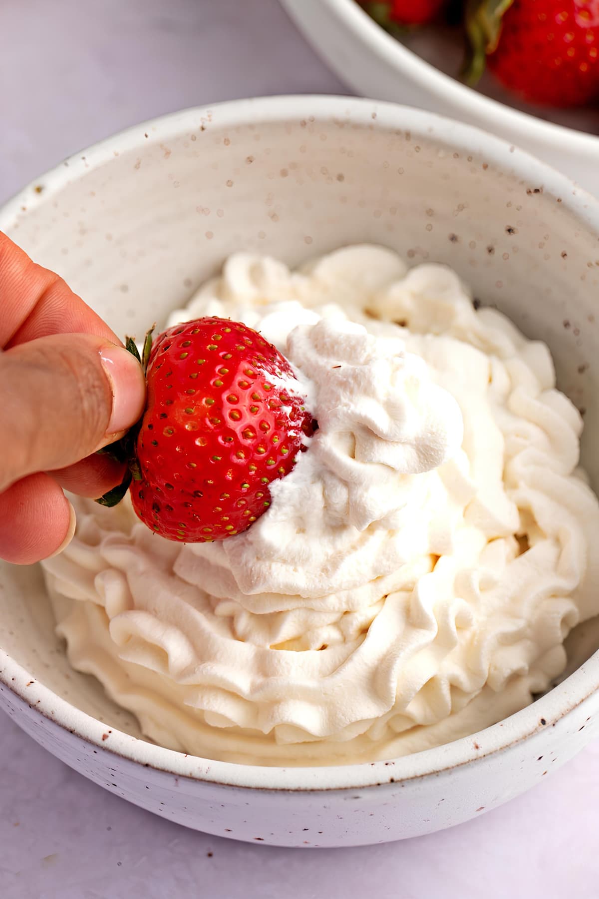 Woman Dipping Strawberry into a Bowl of Whipped Cream