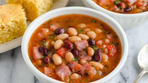 Two bowls of 10-bean soup with cornbread on the side.
