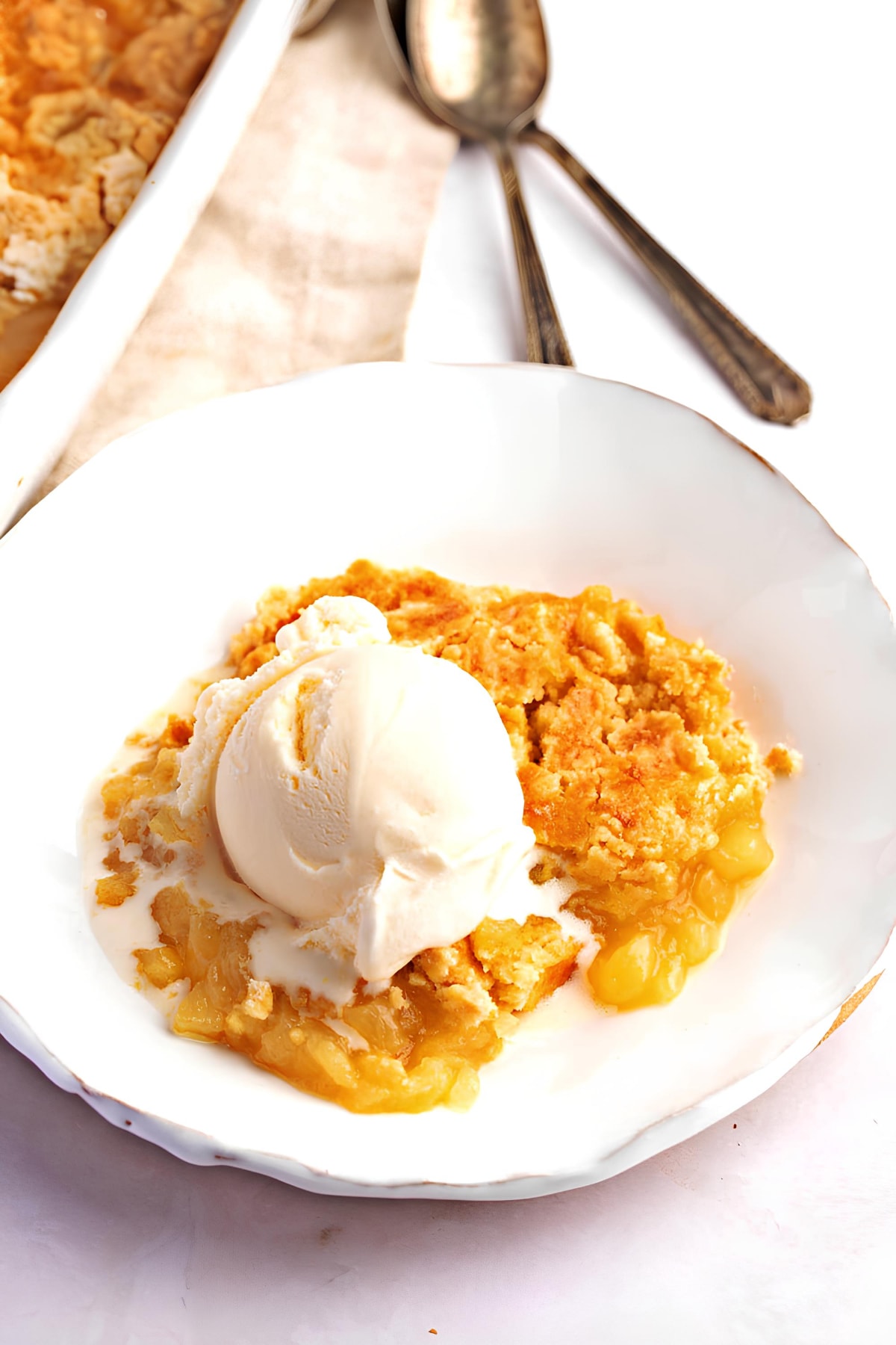 A Piece of Pineapple Dump Cake with Ice Cream on a Plate