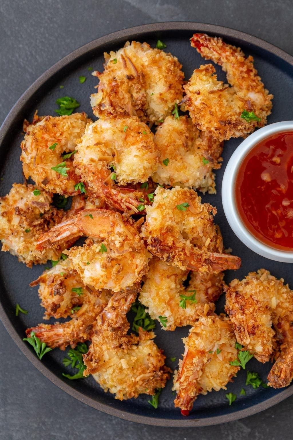 Homemade Air Fryer Coconut Shrimp on a round tray with a bowl of dipping sauce