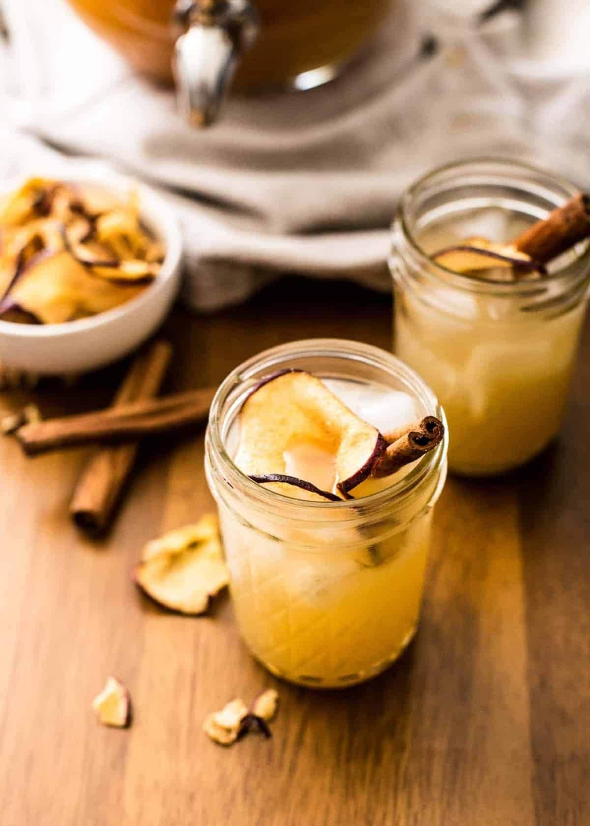 Glasses of iced Apple Cider Punch with Bourbon garnished with dried apple slices and cinnamon stick. 