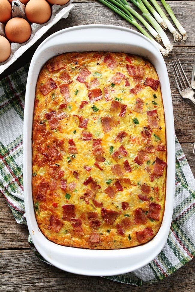Bacon, Potato, and Egg Casserole with fresh  green onions and eggs on a wooden table