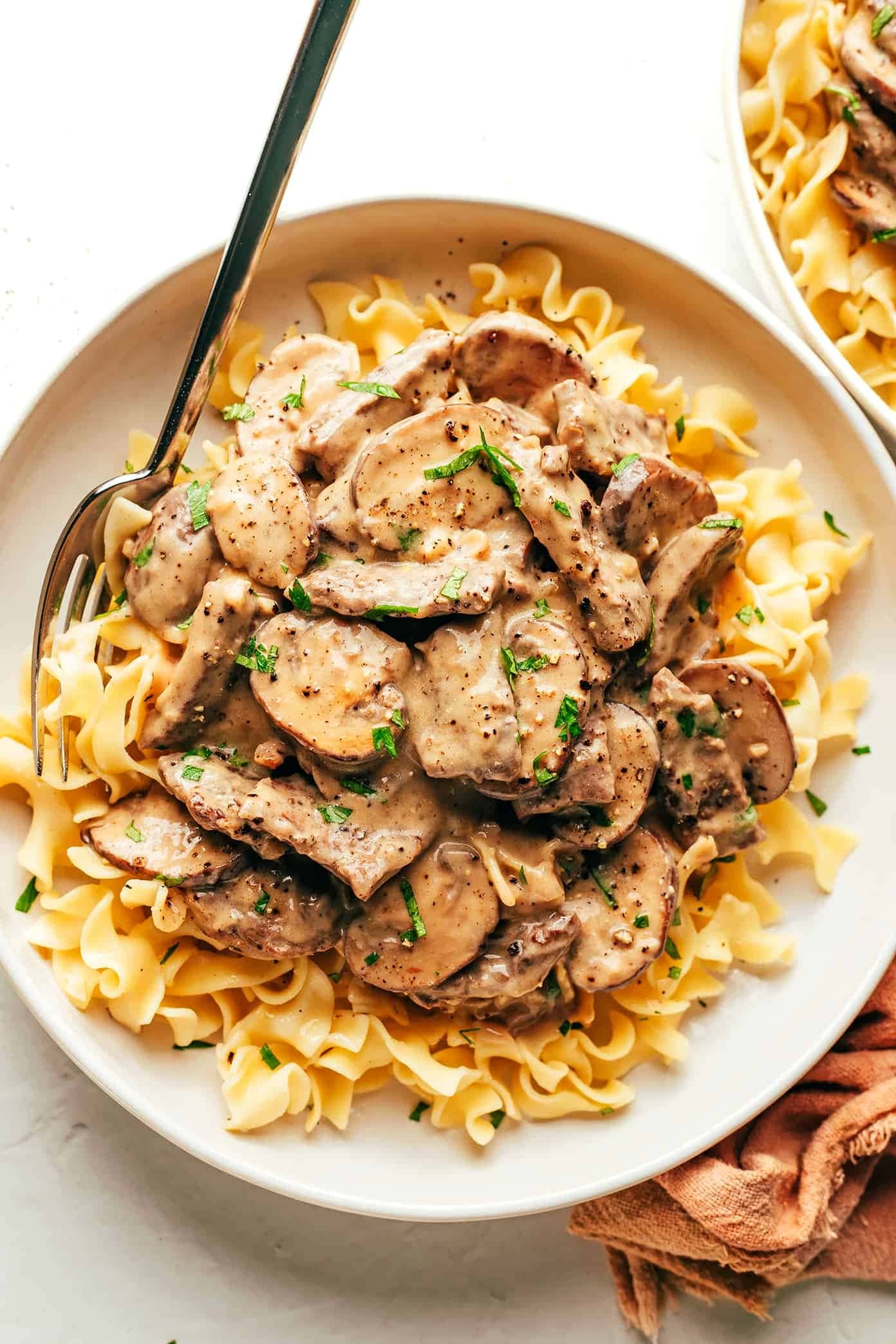 Top view of a serving of beef stroganoff served on top of noodles. 