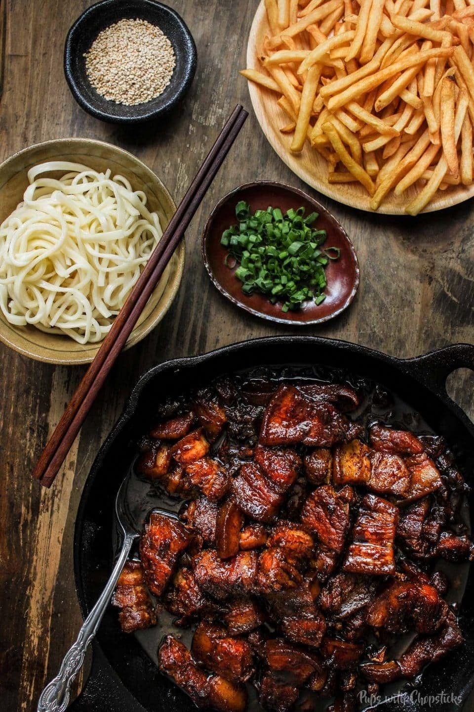 Beer Braised Slow Cooker Pork Belly on a cast iron with fries and noodles on the side