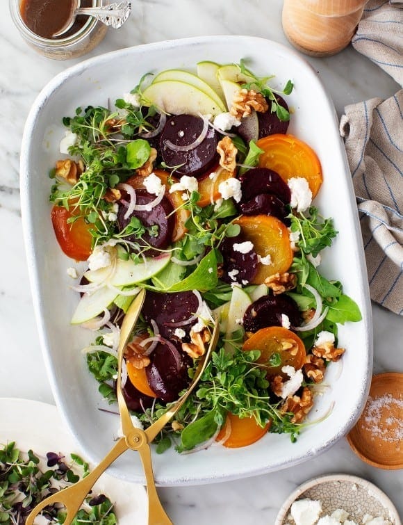 Roasted beet salad with mixed with pear, walnuts, and feta layered over leafy green and micro-sprouts.