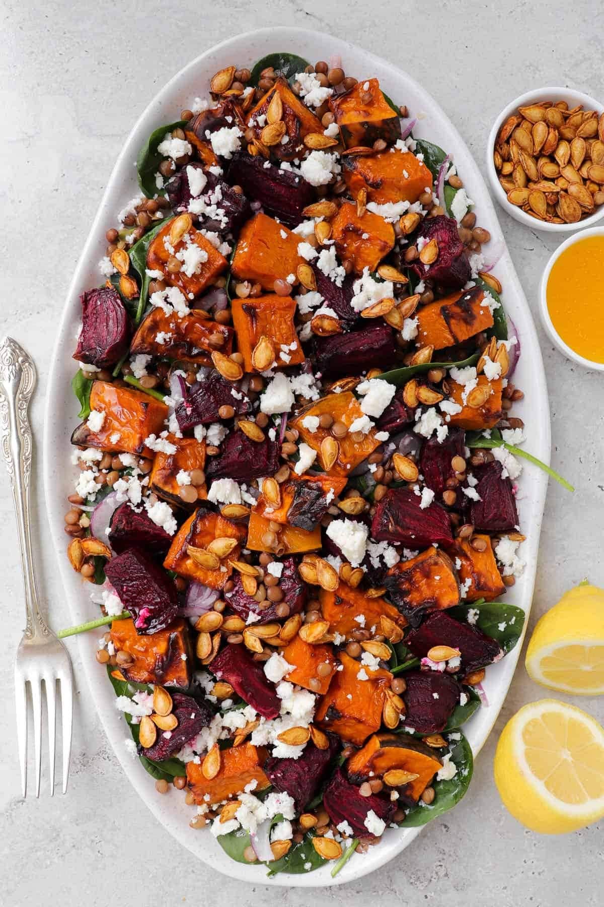 Roasted beetroot and pumpkin salad in a plate made with roasted pumpkin, beets, spinach, lentils, and feta. 