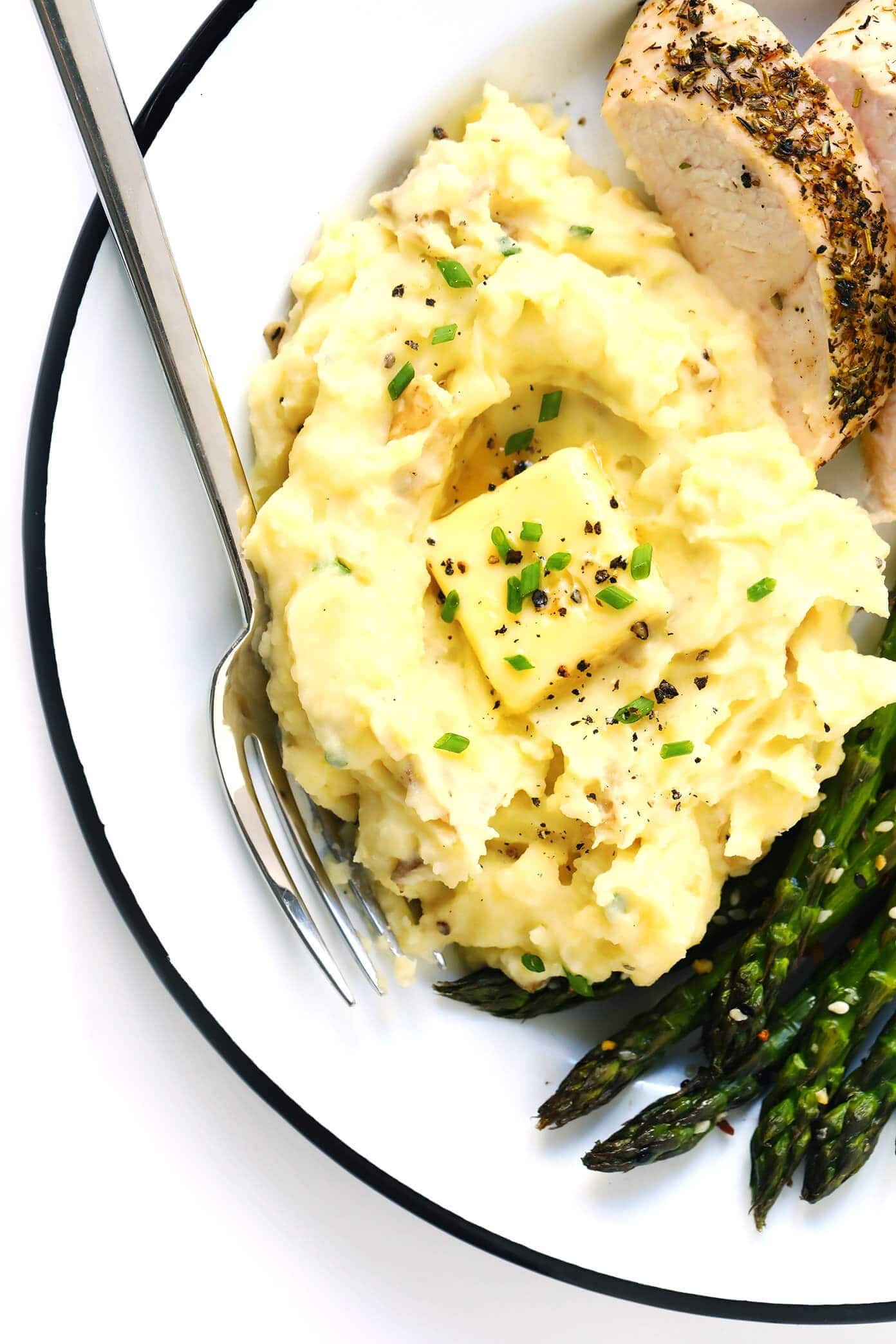 Mashed potatoes with roasted chicken and asparagus served on a white plate. 