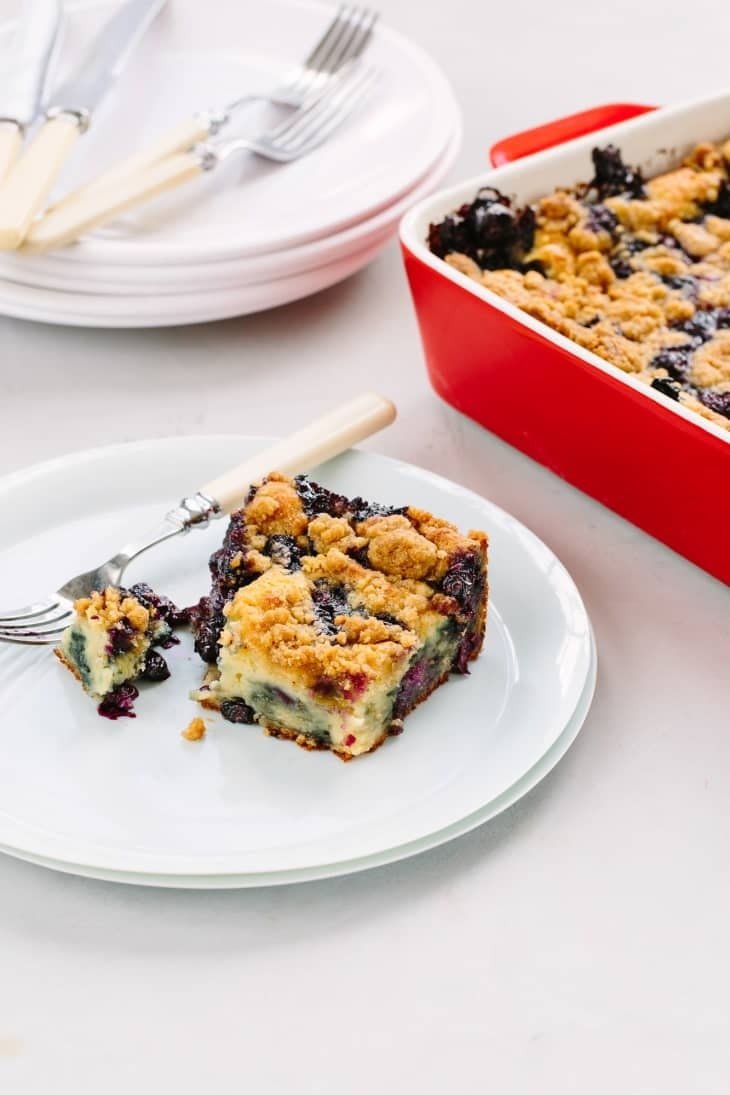Blueberry pancake casserole slice on a white plate with fork. 
