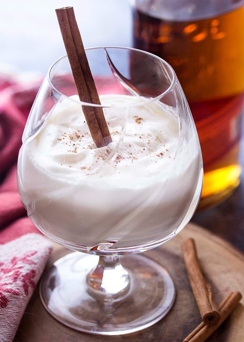 A glass of bourbon milk punch with cinnamon stick. 