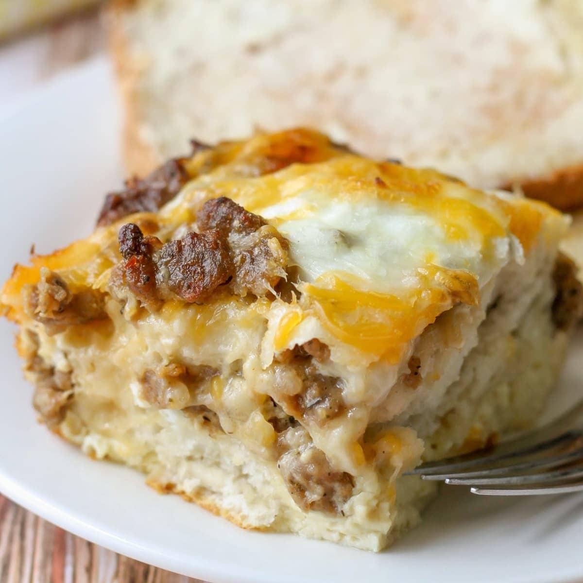Slice of biscuit egg casserole with layers of eggs, cheese and sausage on top. 