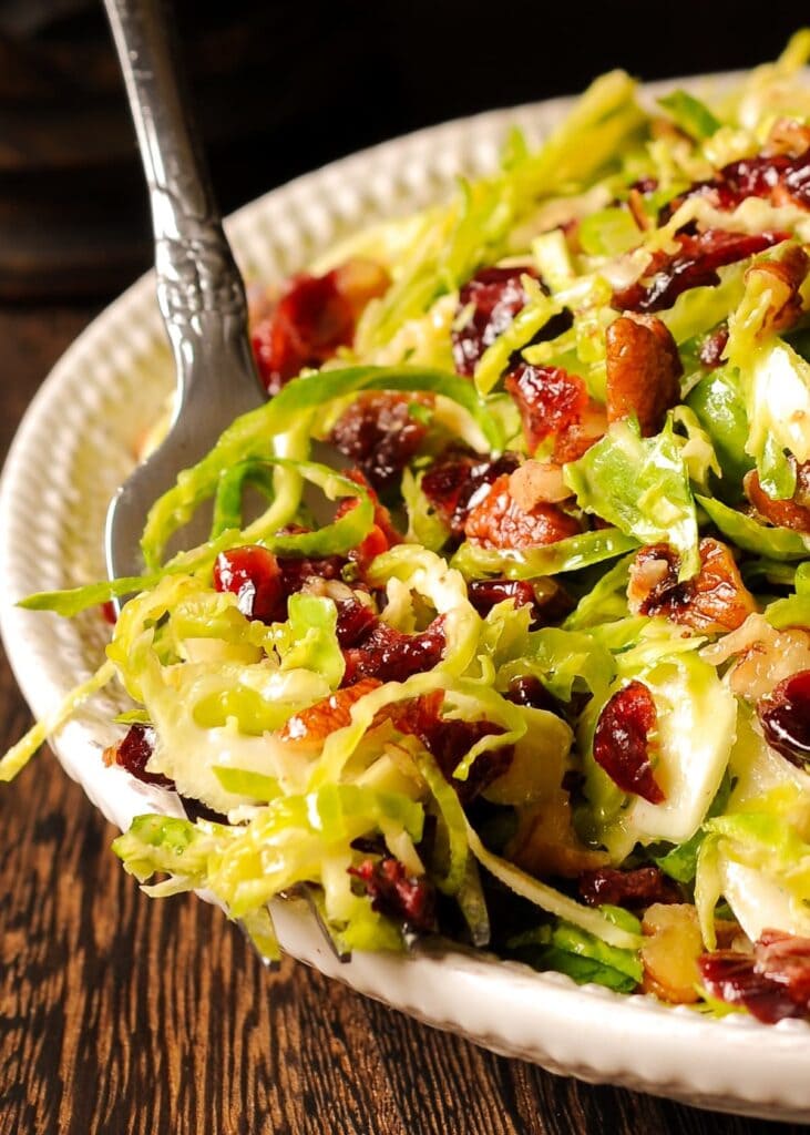 Brussels sprouts salad with cranberries served on a plate with fork. 