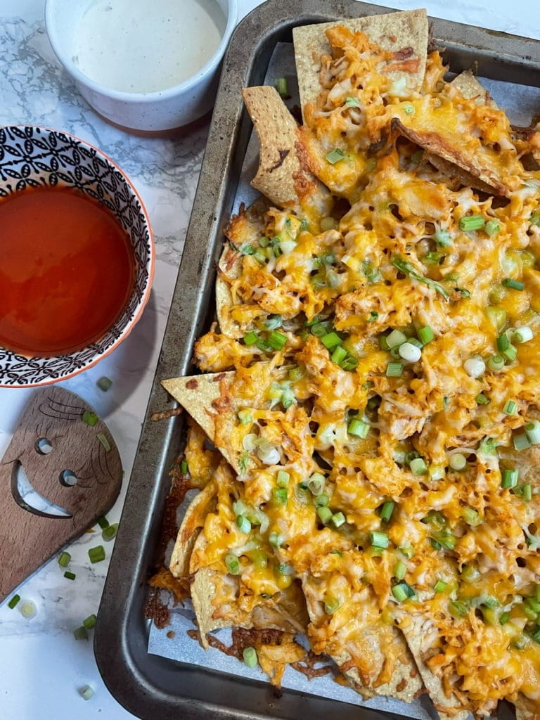Buffalo Chicken Nachos served on a sheet pan with loads of cheese. 