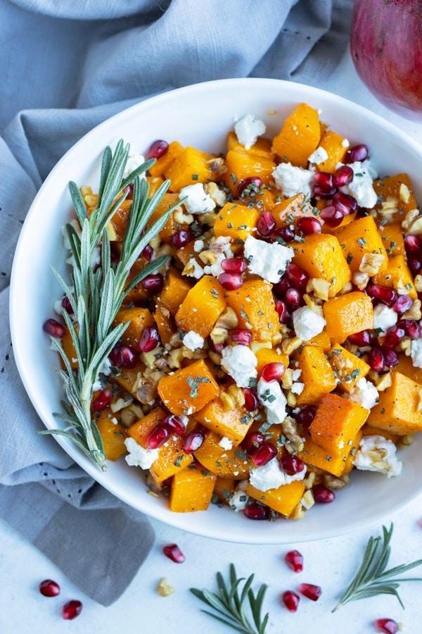 Roasted butternut squash with goat cheese on a plate with pomegranate arils. 