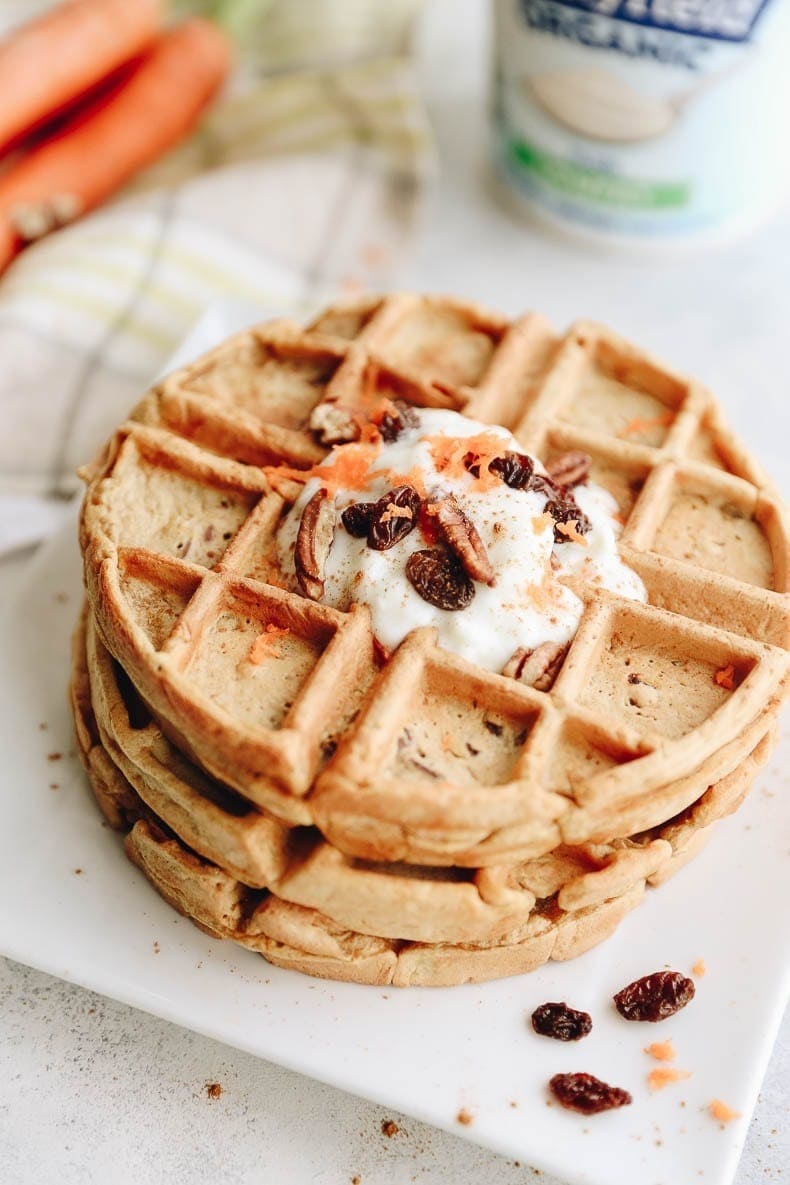 Stacks of homemade Carrot Cake Waffles with raisins, pecans and grated carrots on top