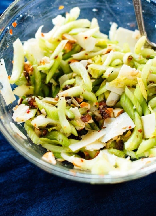 Celery salad with dates, almonds and parmesan in a glass bowl. 