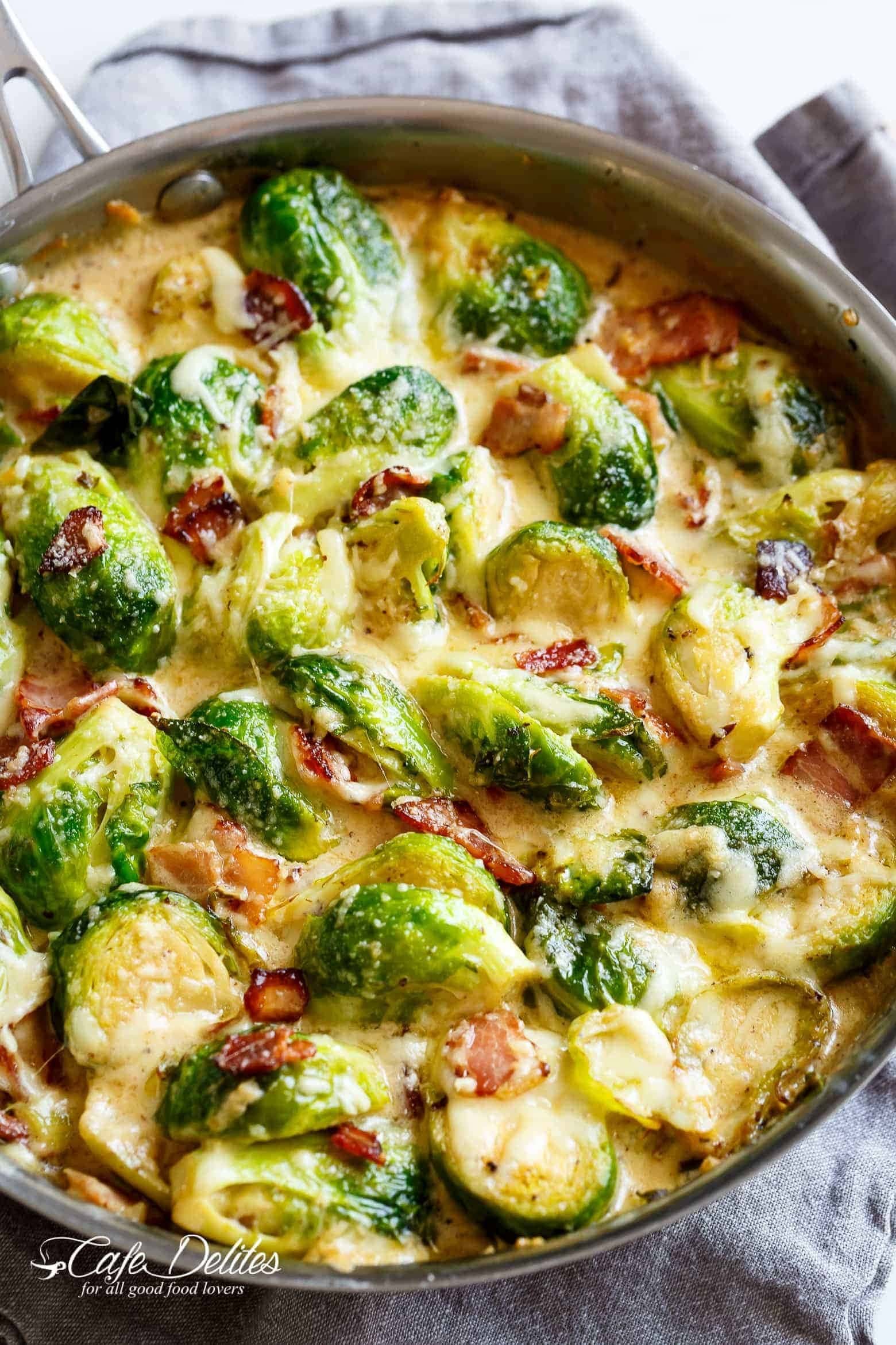 Brussel sprouts with creamy sauce and bacon cooked on a pan. 