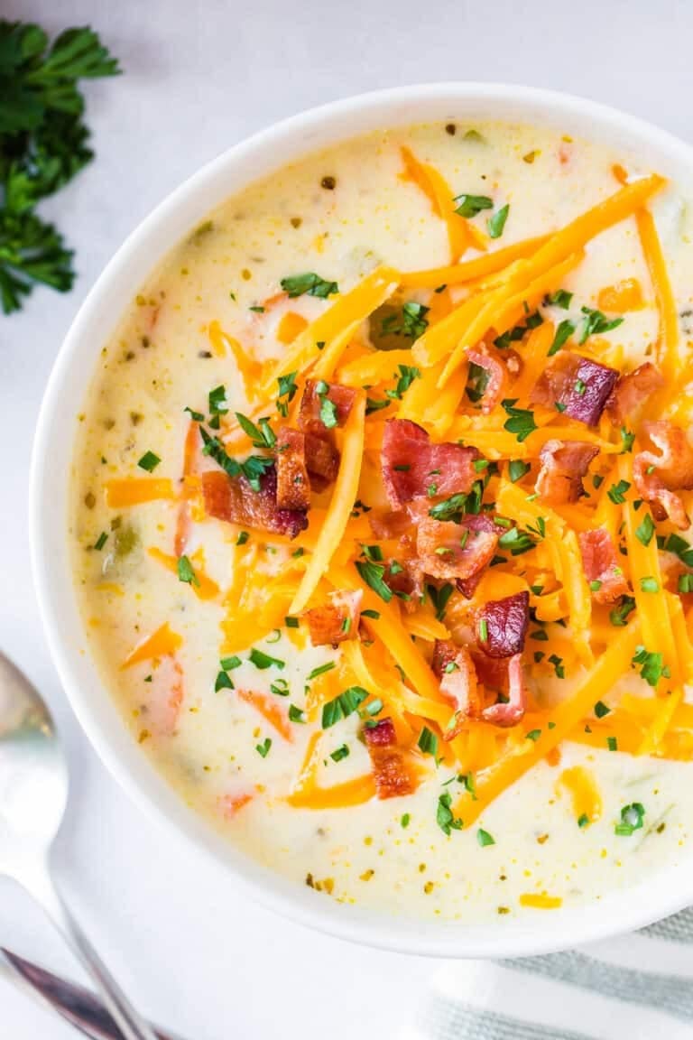 Chicken chowder in bowl topped with grated cheese and crispy bacon bits. 