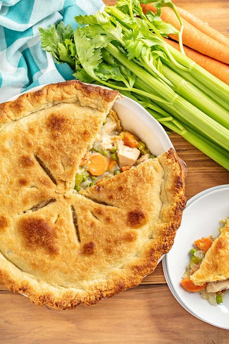 A Platter of Chicken Pot Pie with fresh celery and carrots on a wooden table