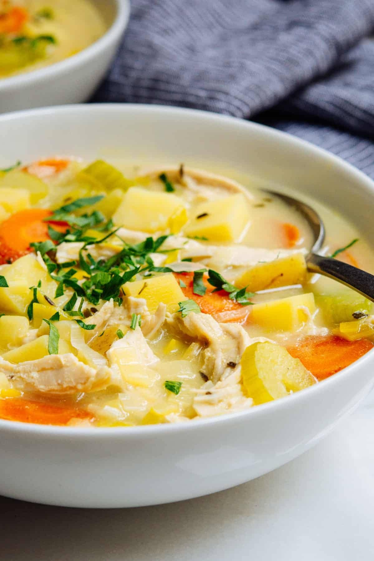 A bowl of chicken potato soup with spoon. 
