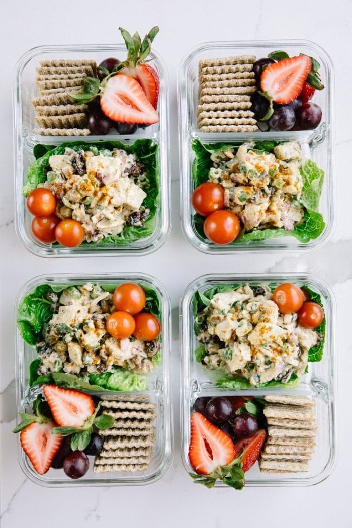 Curried chicken salad meal prep with lettuce, crackers, and fresh fruit.