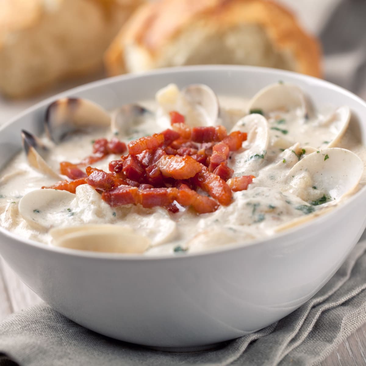 New England clam chowder in a bowl topped with bacon strips. 