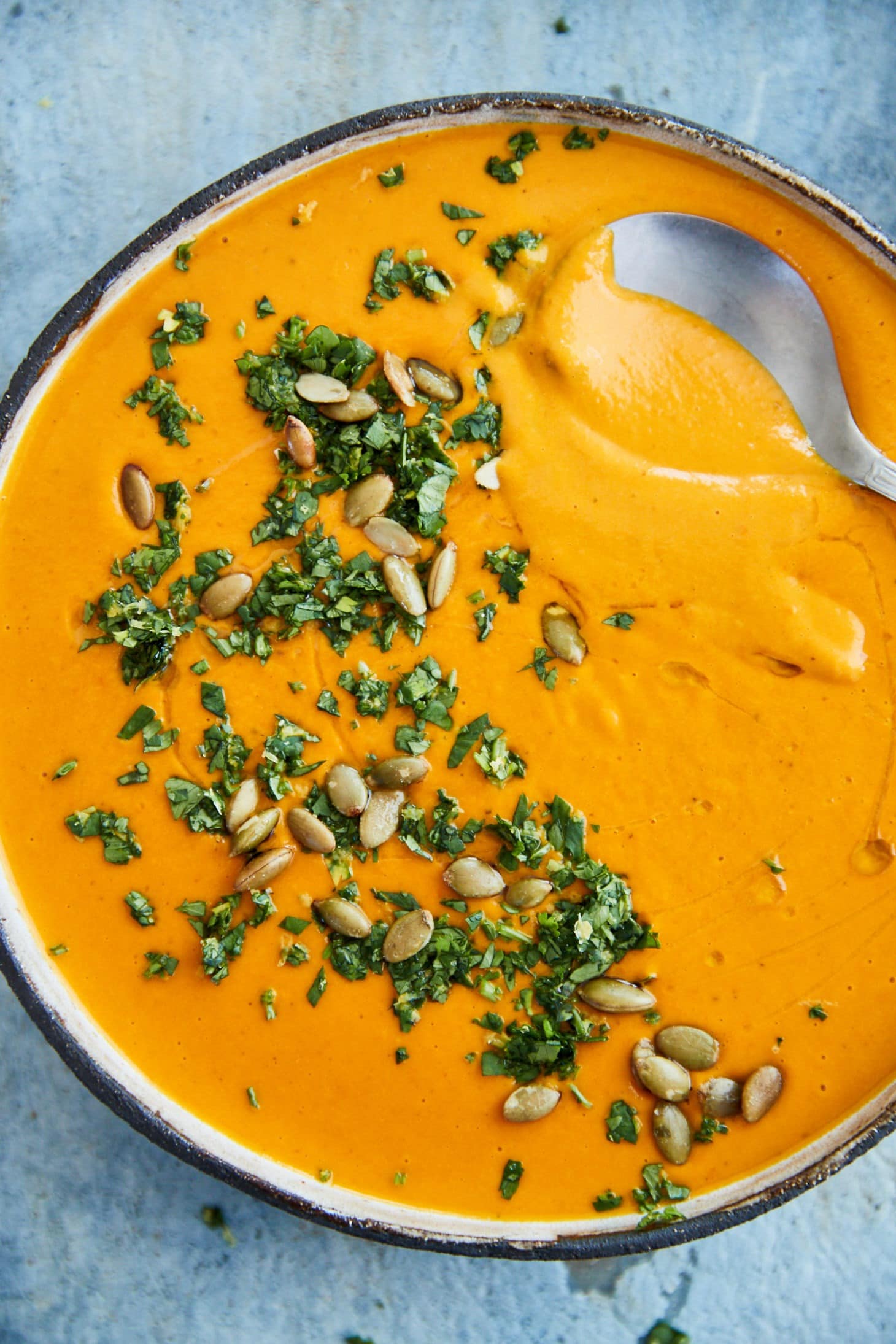 Bowl of Coconut Curry Carrot Soup topped with cilantro and pepitas