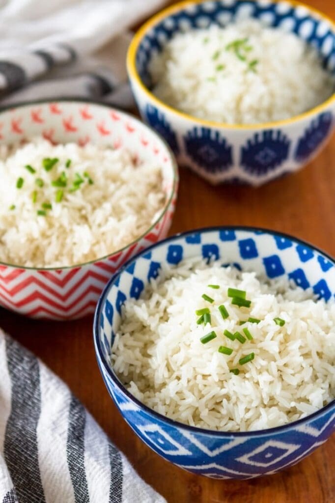 Three bowls of coconut rice topped with chopped onion leeks. 
