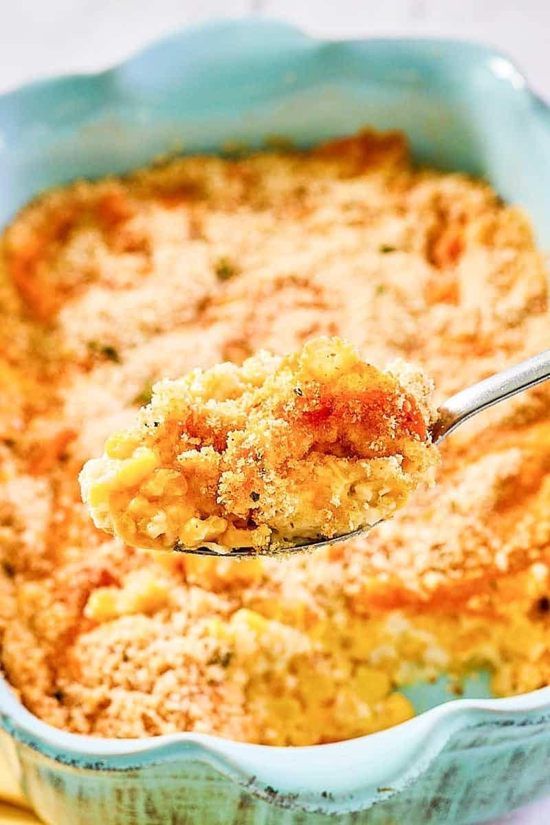Corn au gratin in a baking dish scooped with a spoon. 