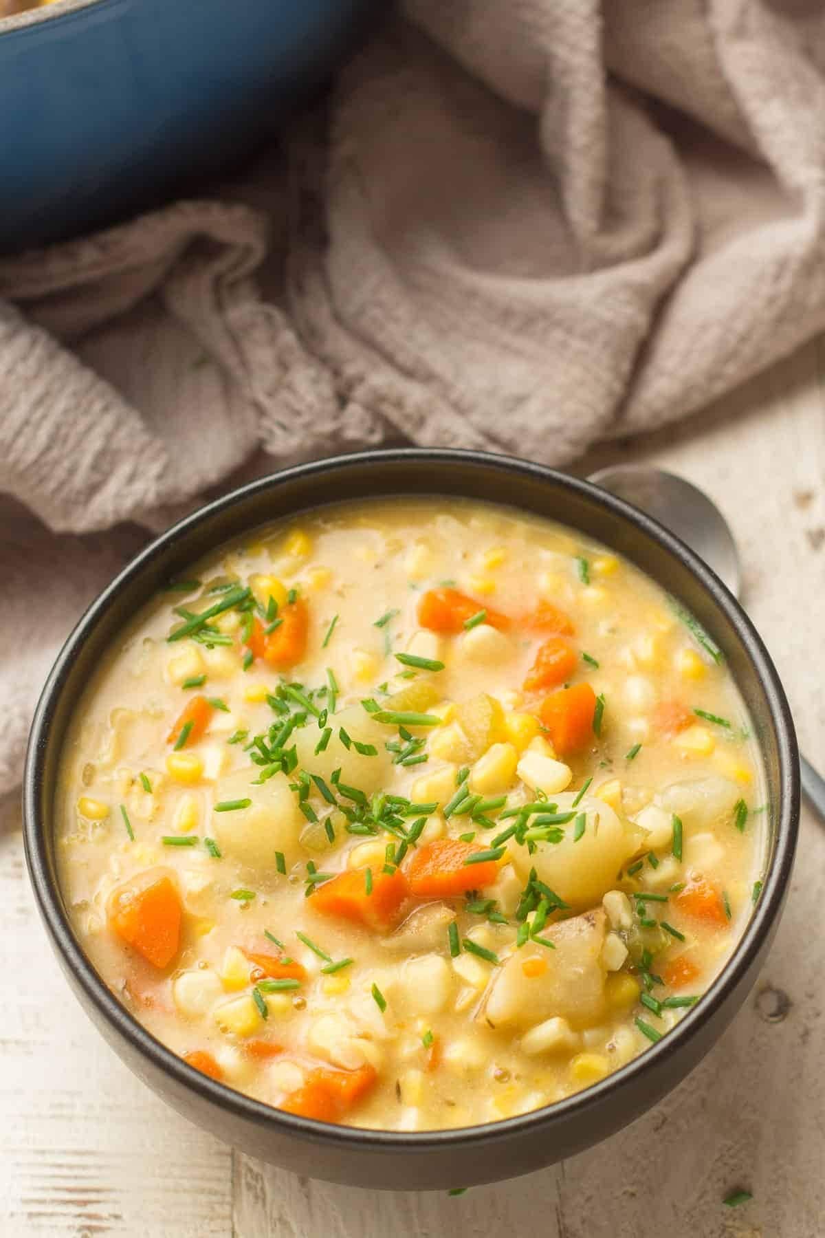 Bowl of homemade Corn Chowder with potatoes, carrots, corn kernels and garnished with chopped chives