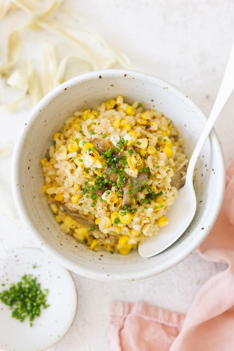 A bowl with corn risotto with roasted shallots.
