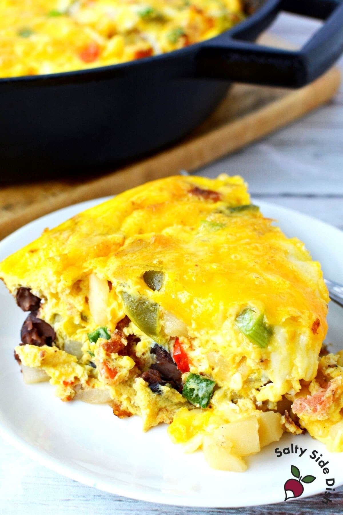 Slice of egg casserole with bacon, bell peppers, diced Russet potatoes, black beans, and plenty of cheese