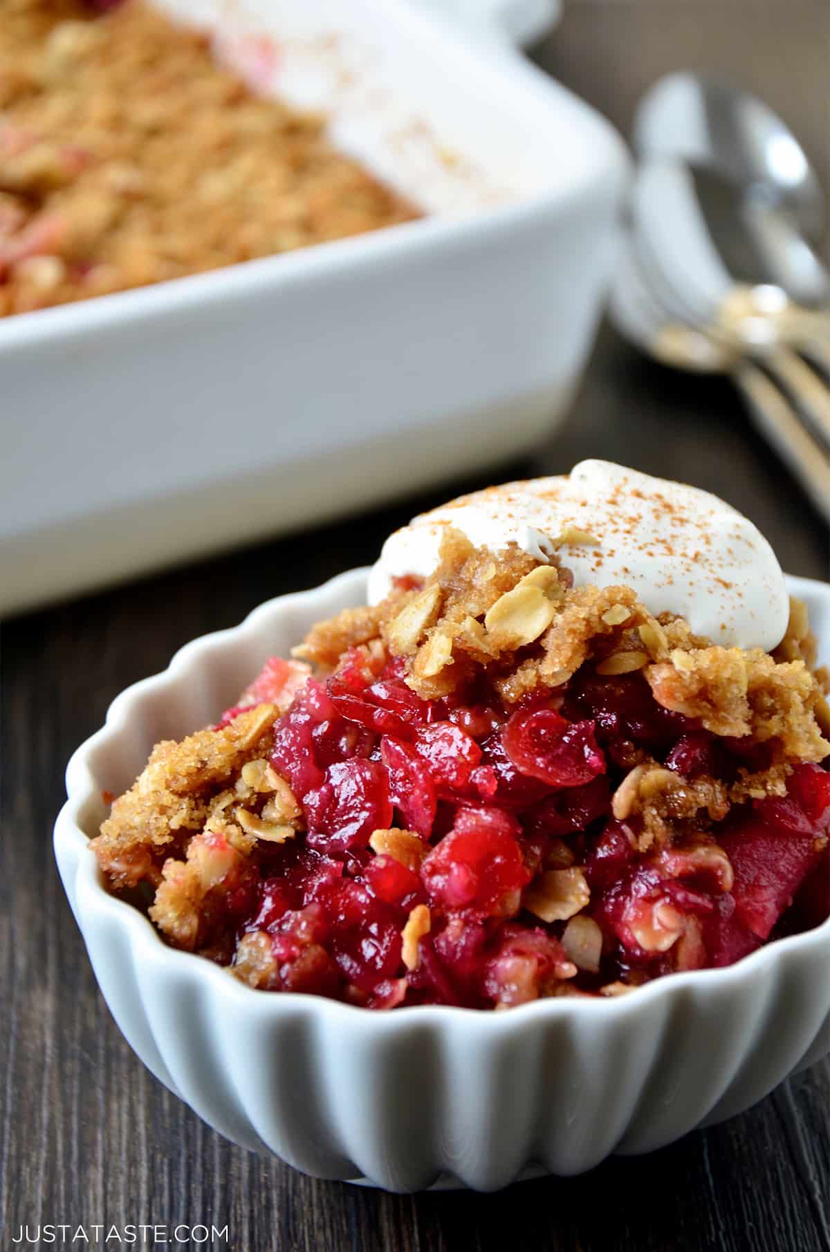 Cranberry crisp in white dish topped with vanilla and cinnamon powder.